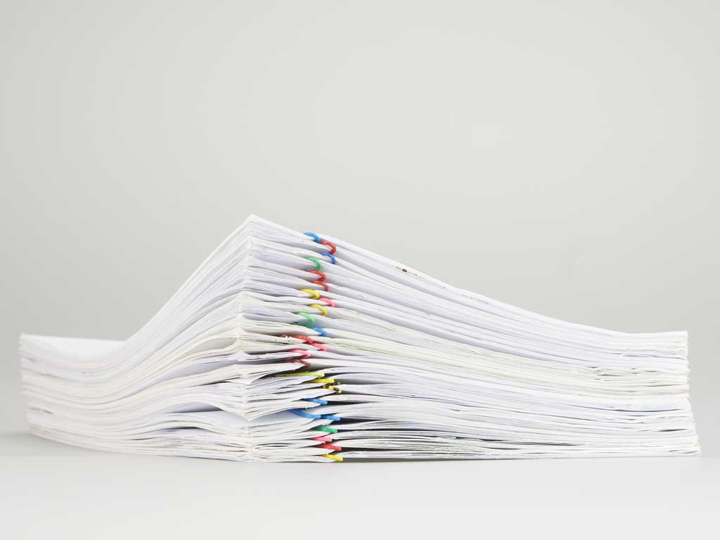 Foto av en hög med pappersbuntar sammanhållna med färgglada gem.